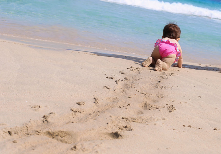 Come fotografare i bambini Bambina gattona sulla spiaggia verso il mare