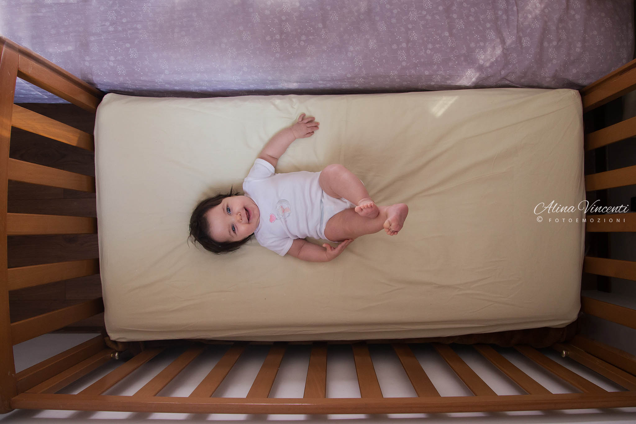 Cambiare Il punto di vista in fotografia bambina che ride sdraiata nel lettino