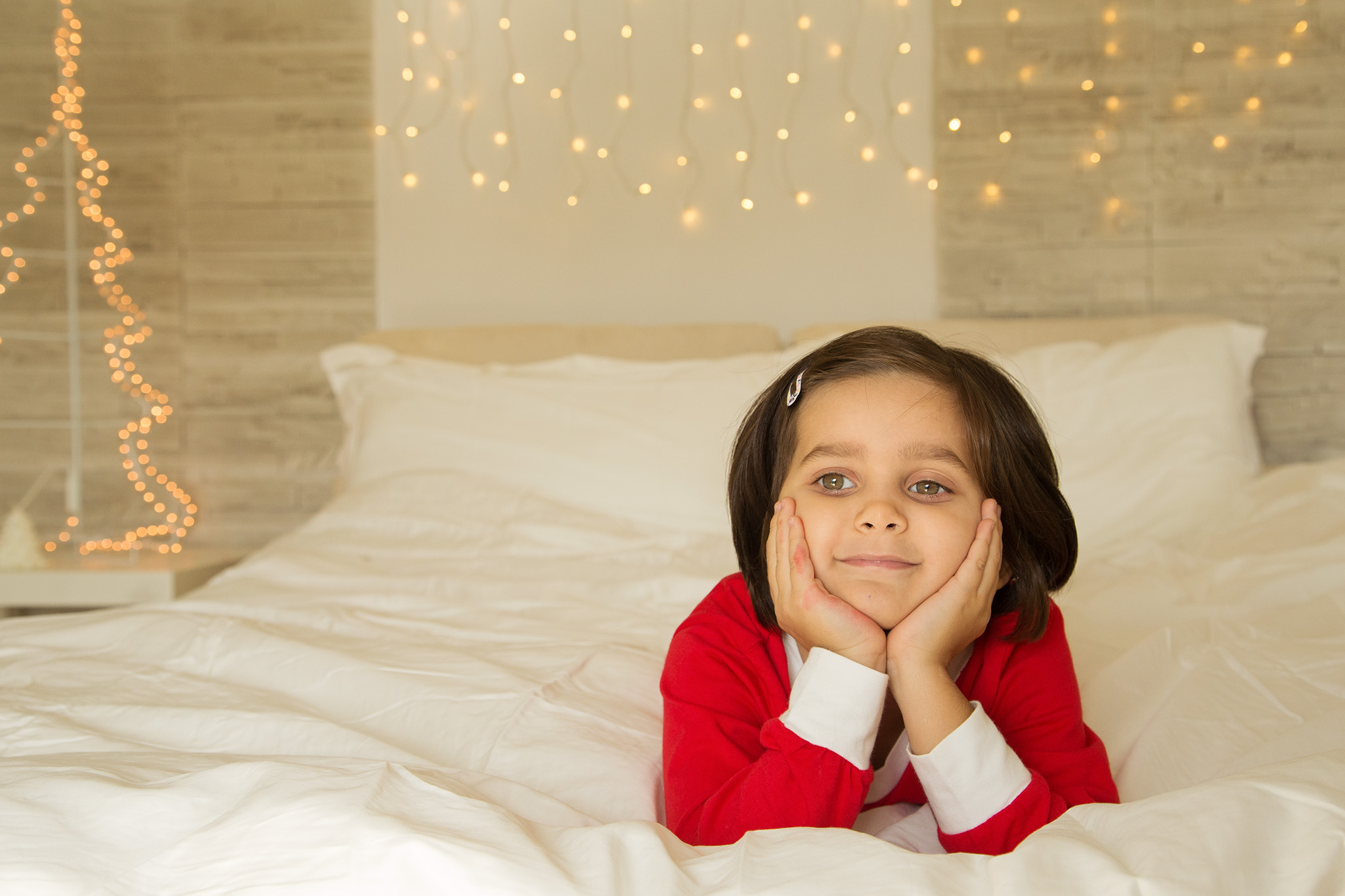 Bimba sul lettone con le luci di Natale