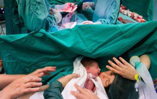 mamma che tocca per la prima volta la figlia nata con un parto cesareo