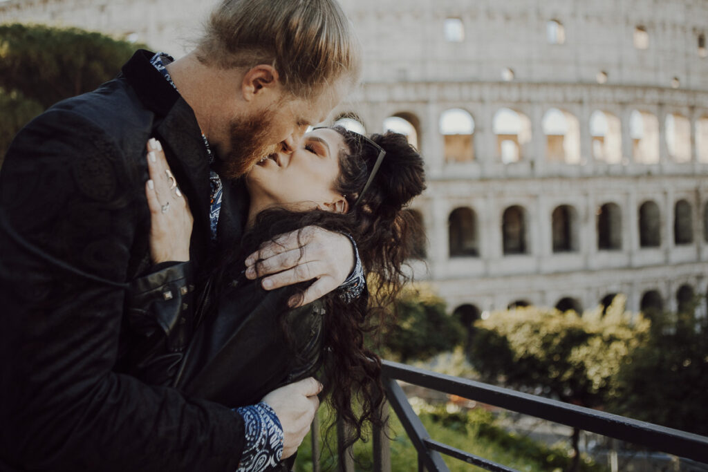 A lovely couple is kissing in front of Colosseo after during a surprise proposal photoshoot in Rome