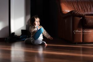 a baby sitting on the floor with a toothbrush in his mouth