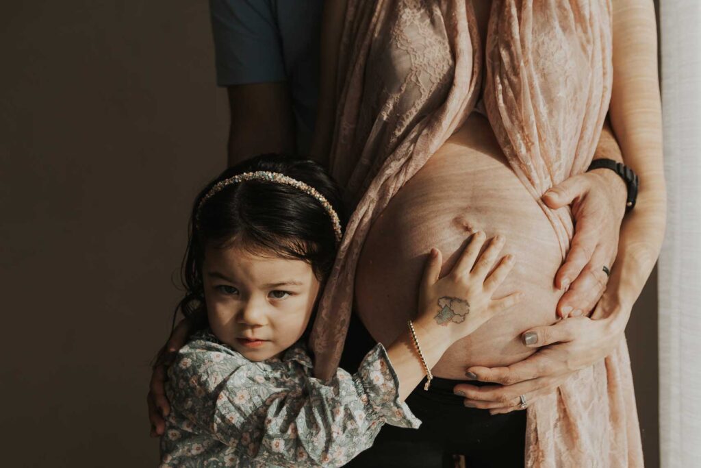 Una bambina accarezza la pancia della mamma in un servizio fotografico di gravidanza Roma