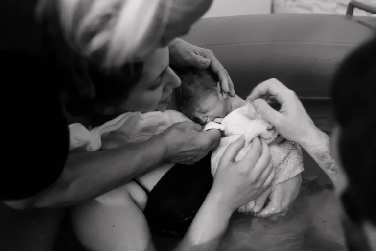 a woman holding a newborn in water fotografia di famiglia Roma
